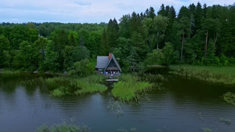 drone flight retreating over the water from a lakeside country house with terrace