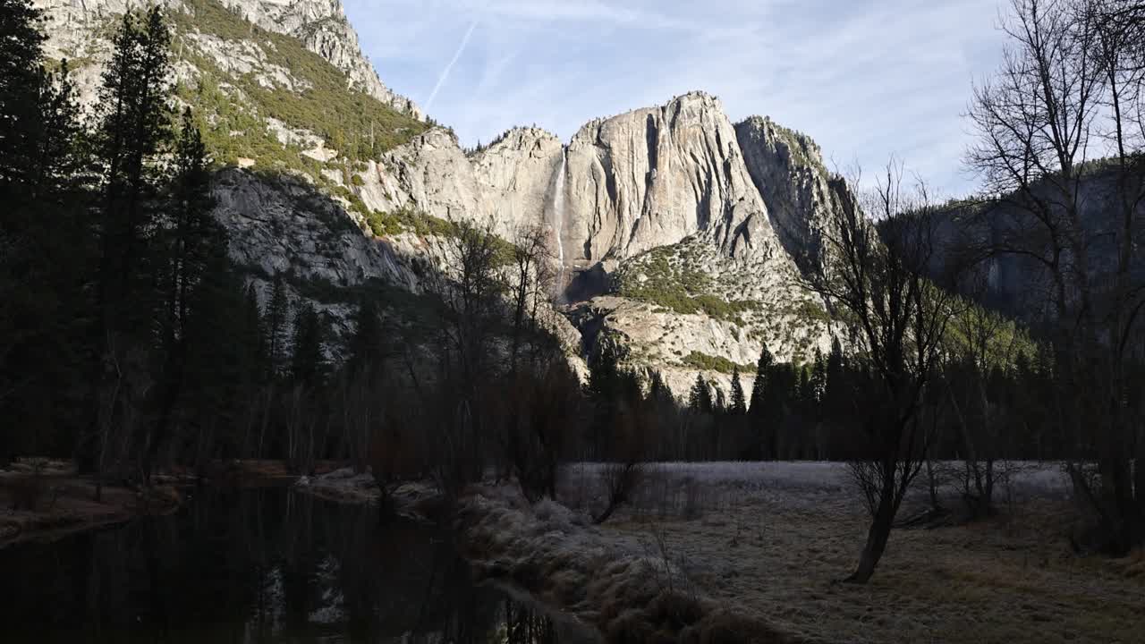 wide shot of upper yosemite falls from afar in winter foliage during sunrise and valley shadows TILT UP