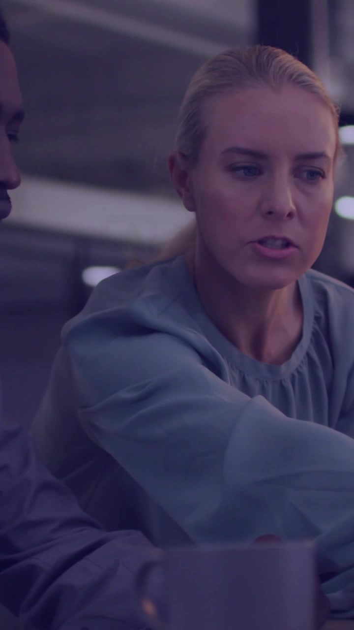 Video verticale: Donna che si protende sul tavolo in un contesto aziendale, presentando un ologramma di icone di CO2 vicino a un collega.