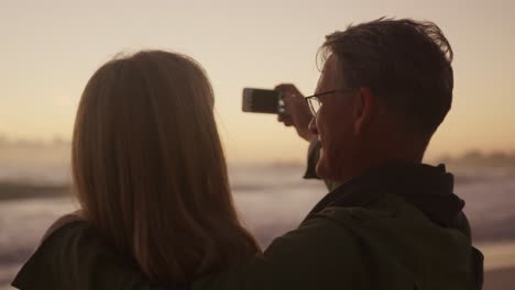 active senior couple taking picture on beach