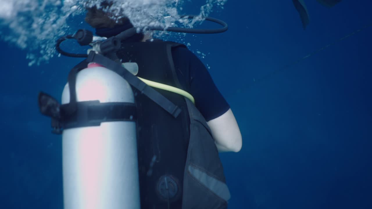 A person scuba diving in blue water
