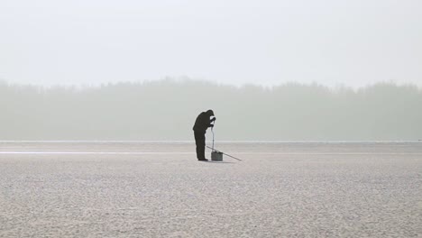 silhouette fisherman on the ice at a frozen lake in winter