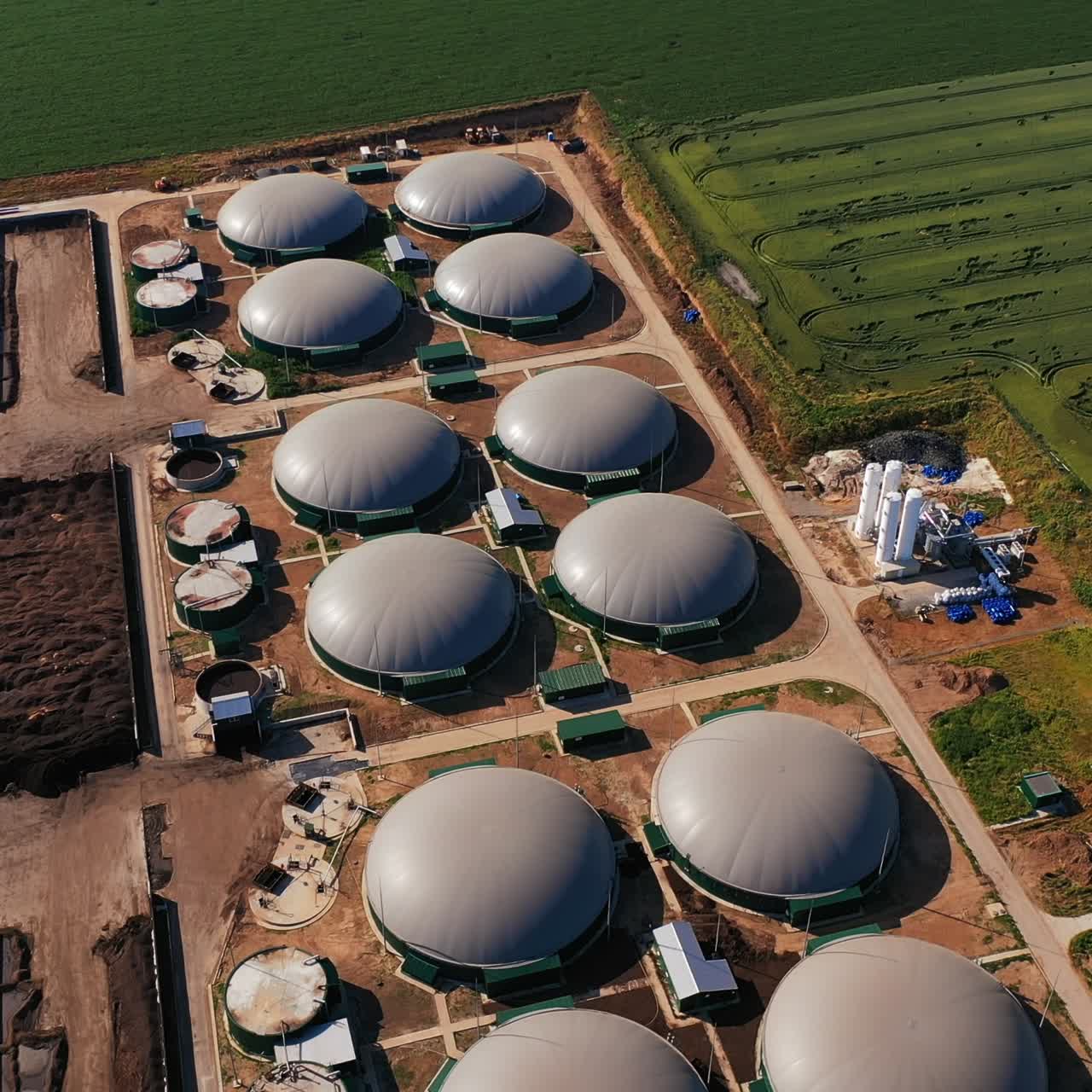 Round tanks of the up-to-date biogas production. Top view on the powerful plant of green energy. Farmlands at the backdrop