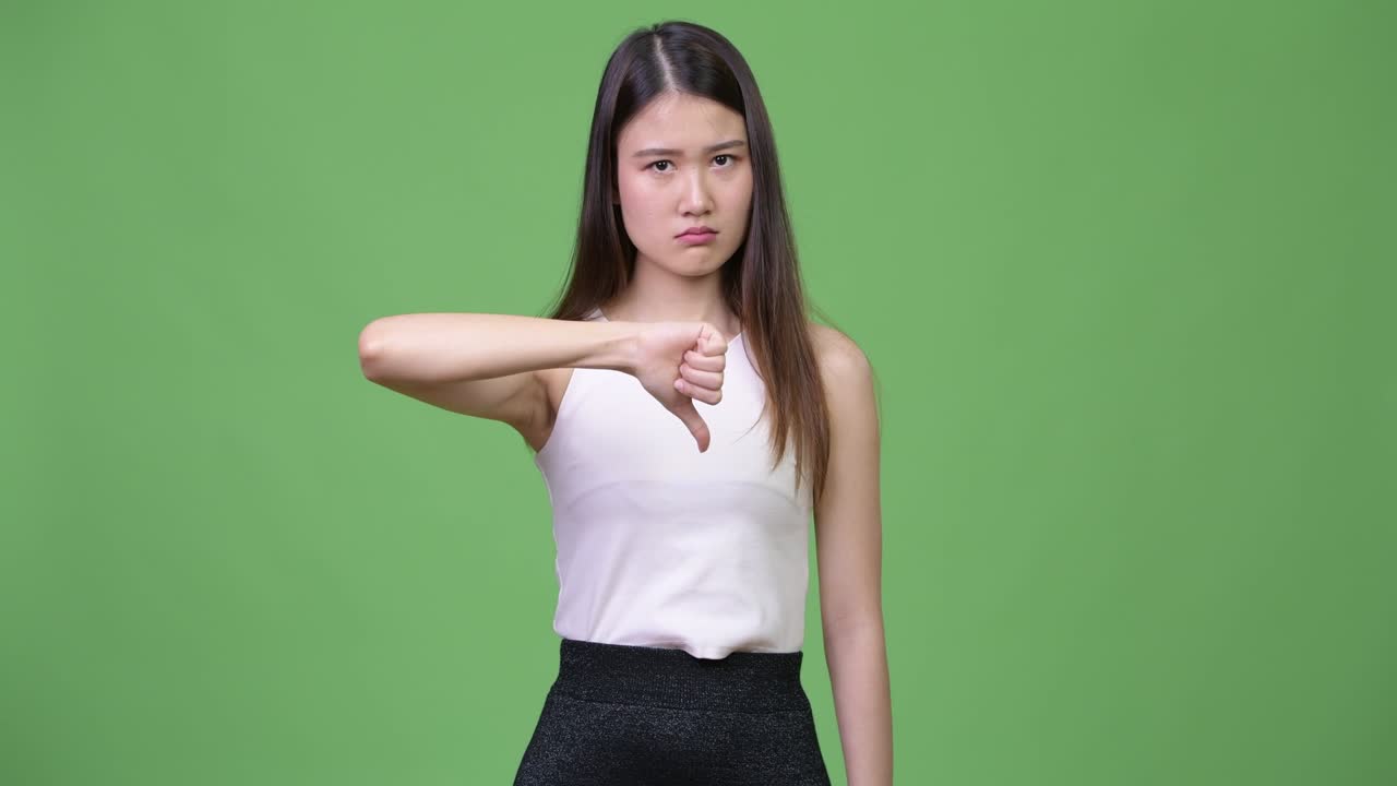 Young beautiful Asian businesswoman giving thumbs down