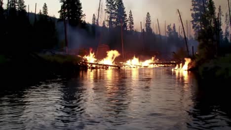 a fierce display of nature's power: a river engulfed in flames surrounded by trees captured in dusk's glow