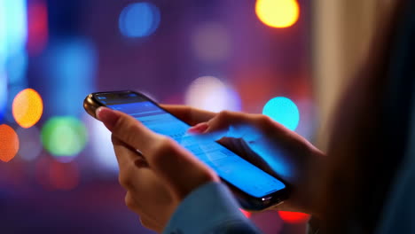 person using smartphone at night with city lights