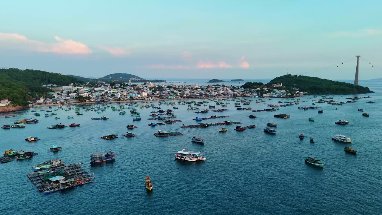 Aerial view of Phu Quoc Island, a fisher village with numerous fishing boats in the water and a cable car station visible on the horizon.The peaceful coastal lifestyle and marine activity, in Vietnam.