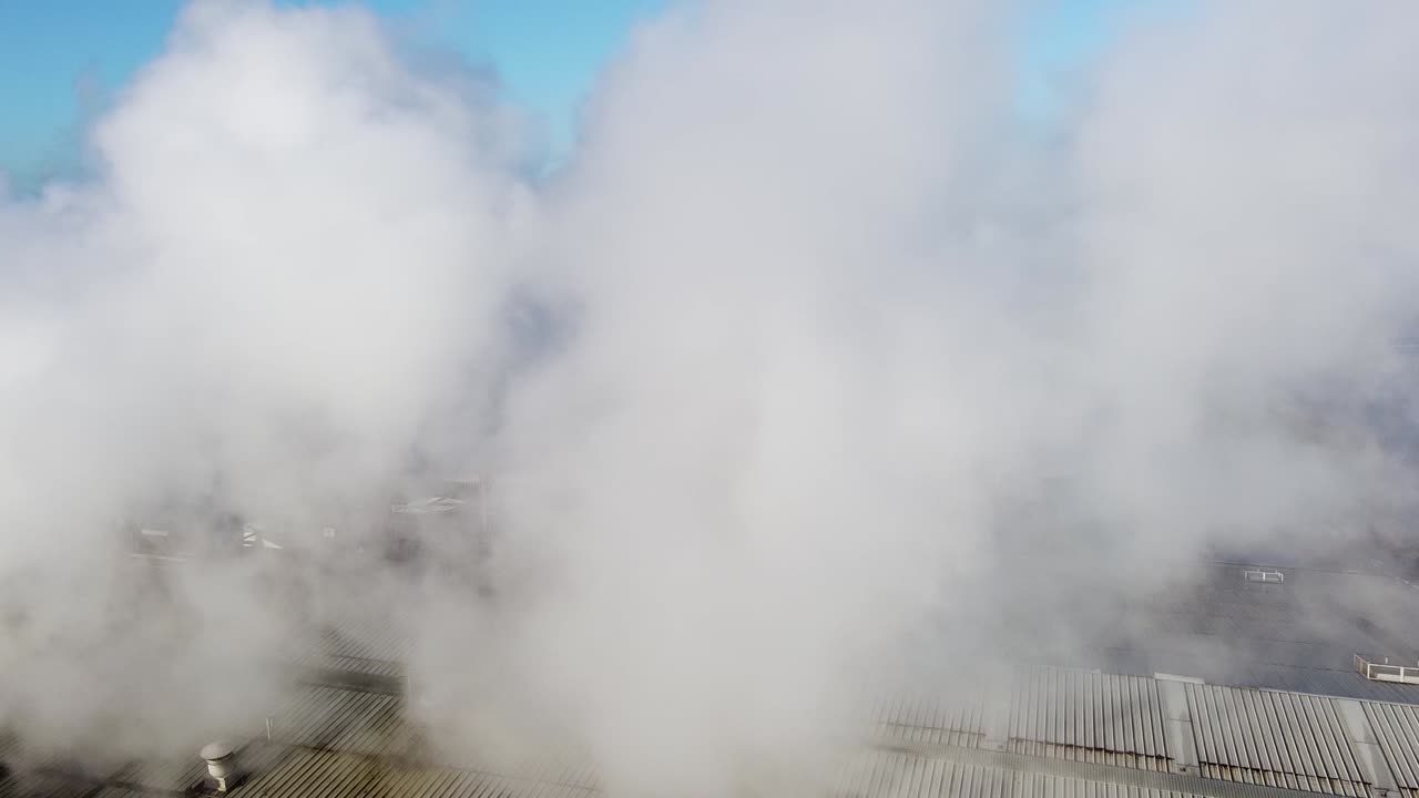 창고 위의 굴뚝에서 나오는 두꺼운 산업 연기