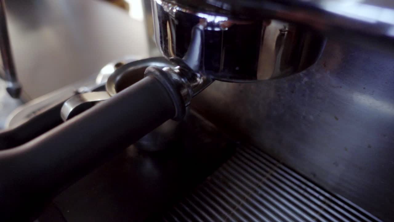 Estrazione di un espresso in primo piano da una macchina da caffè in una piccola caraffa in acciaio inossidabile. Preparazione in stile barista con un ricco getto di crema, workflow da bar e preparazione di bevande calde