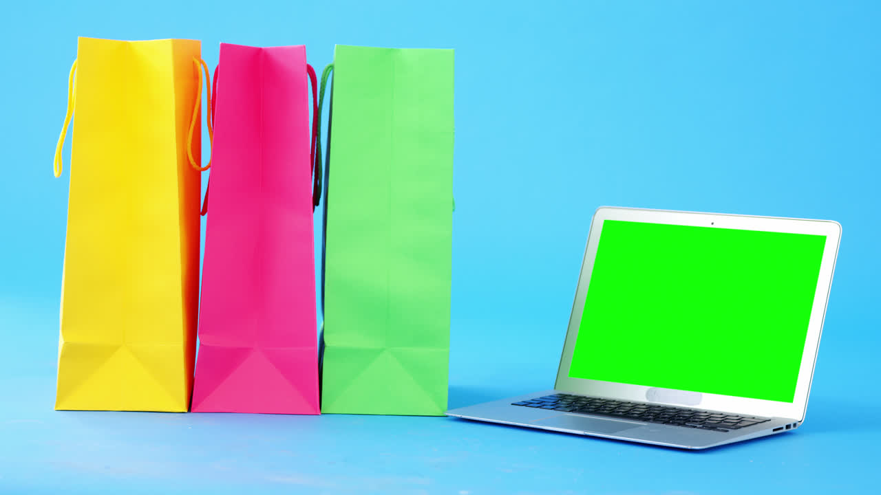 bolsas de compras multicolores y computadora portátil con fondo azul