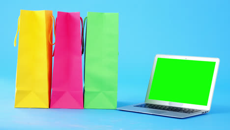 Bunte-Einkaufstaschen-Und-Laptop-Auf-Blauem-Hintergrund