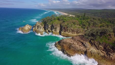 Vista-Aérea-De-La-Costa-Salvaje-Con-Acantilados,-Bosques,-Agua-Azul-Turquesa-Y-Olas-Salpicando