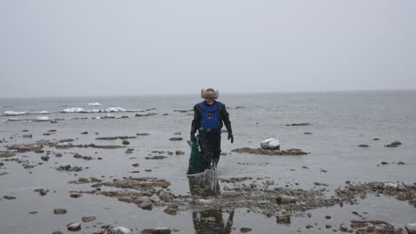 fisherman with a full grid of seafood is on the beach in winter