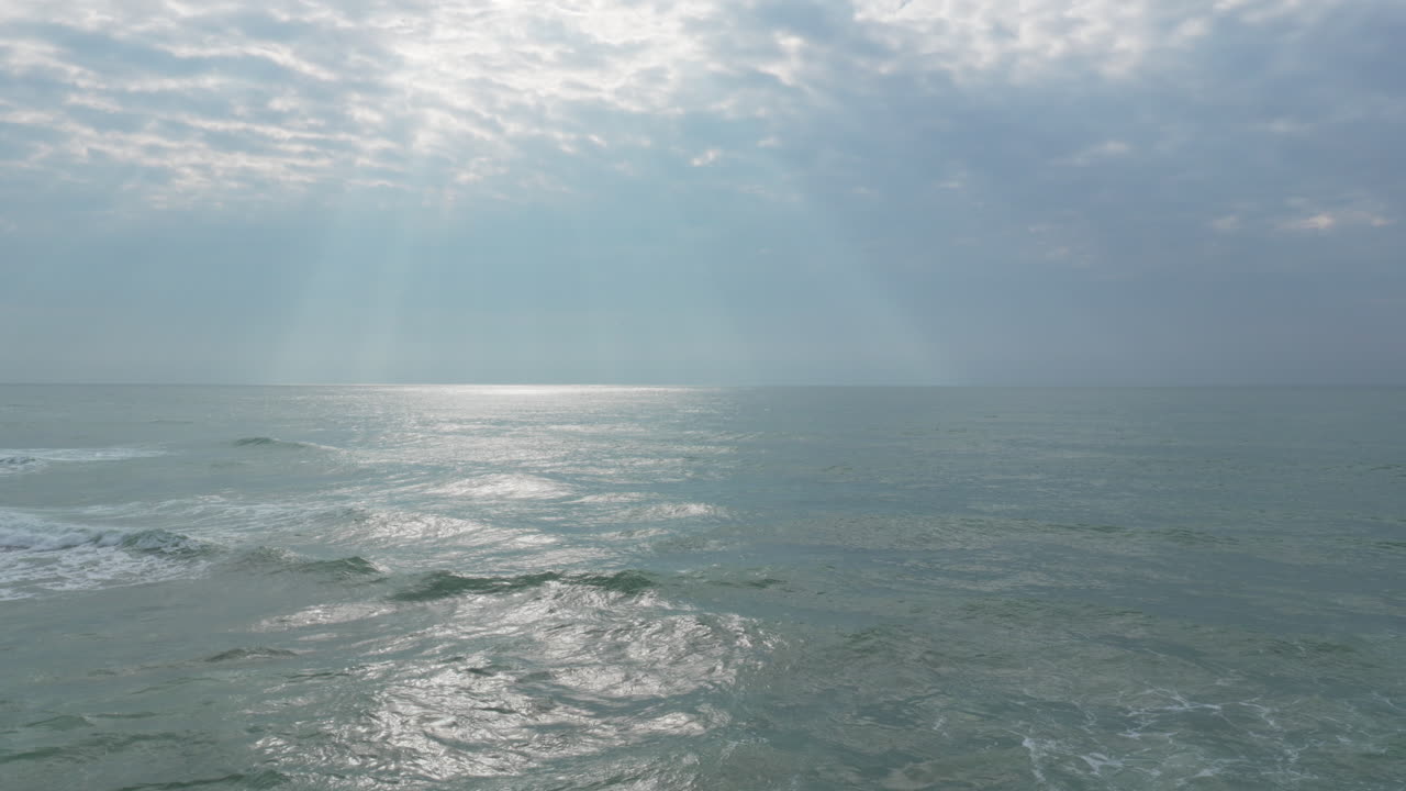 태양 빛은 극적인 아침 동안 잔잔한 바다 파도에 반사