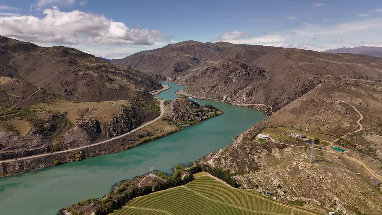 Scenic 4K aerial drone footage of the turquoise Clutha River winding through rugged mountains in Central Otago, New Zealand. Features vineyards and arid landscapes. Ideal for travel and nature