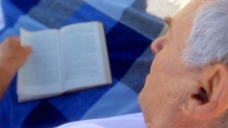 Close-up-of-active-senior-Caucasian-man-reading-a-book-on-the-beach-4k
