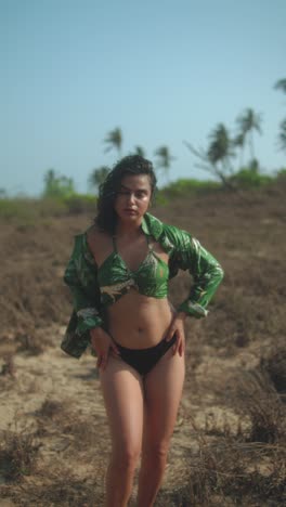 young woman posing on the beach, wearing green shirt and bikini, sun shining