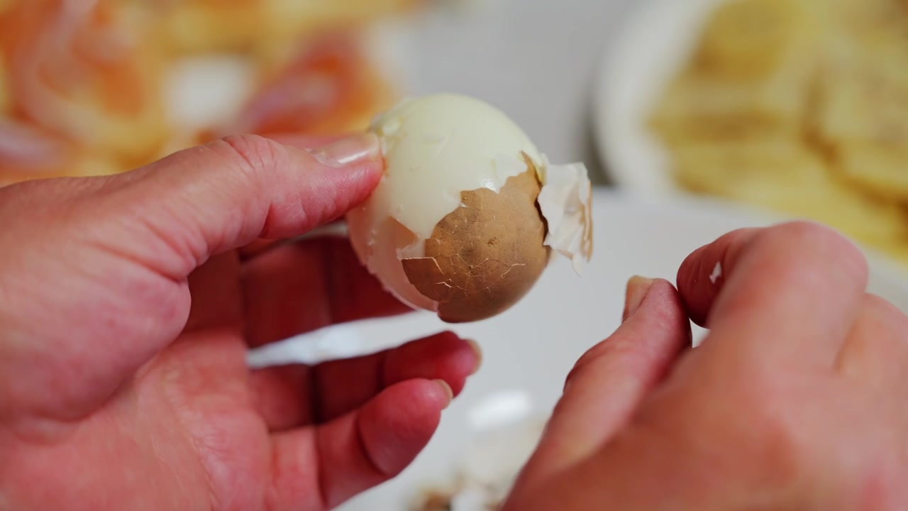 Close view shows peeling egg shell revealing smooth surface for simple meal