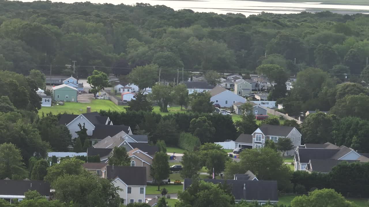Aerial view of suburban American neighborhood with single-family homes, green lawns and tree-lined streets in summer daylight. Wide shot. Cloudy morning in New Jersey