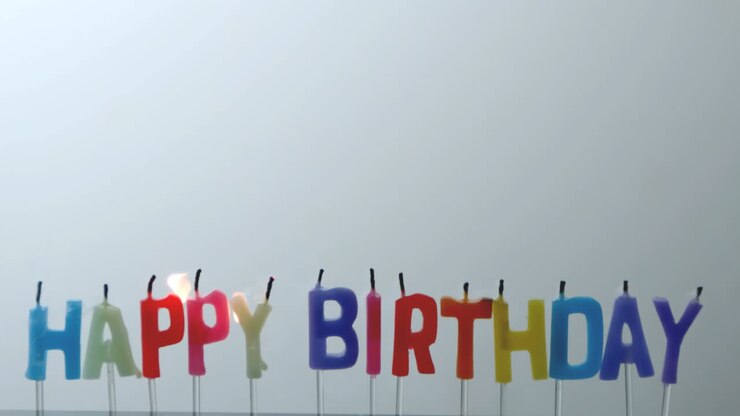 Colourful happy birthday candles being blown out
