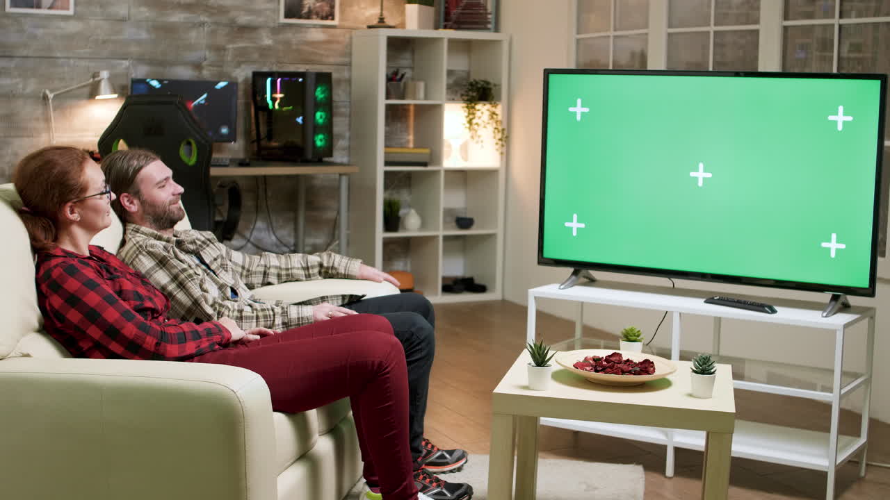 Couple watching TV with green screen in living room