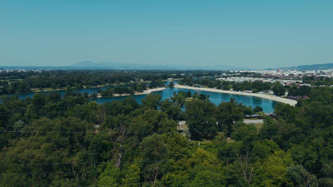 aerial - dense green forest in Zagreb with view of Lake Jarun and urban skyline in summer