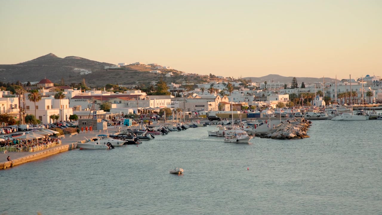 Vista all'ora d'oro di un pittoresco porto fiancheggiato da barche e architettura tradizionale sul lungomare in una città costiera mediterranea.