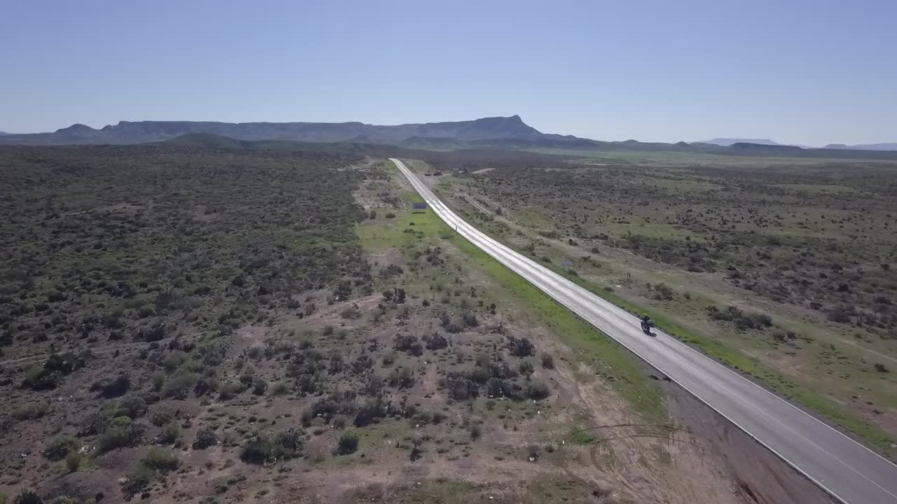motociclista lobo solitario conduciendo por la carretera a través del desierto de baja california, méxico, seguimiento aéreo
