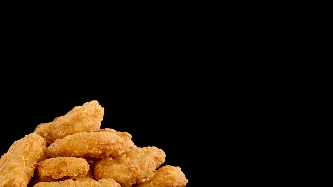Golden brown chicken nuggets spin smoothly against a solid black background. Even, studio lighting highlights the crispy texture. Camera movement creates a seamless, dynamic rotation