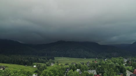 peaceful village with distant view of grazing sheeps and forested mountains in background