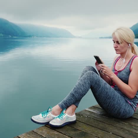 A-Woman-Sits-On-A-Wooden-Pier-Looks-At-The-Mountains-And-Mountain-Lake-In-Austria-1