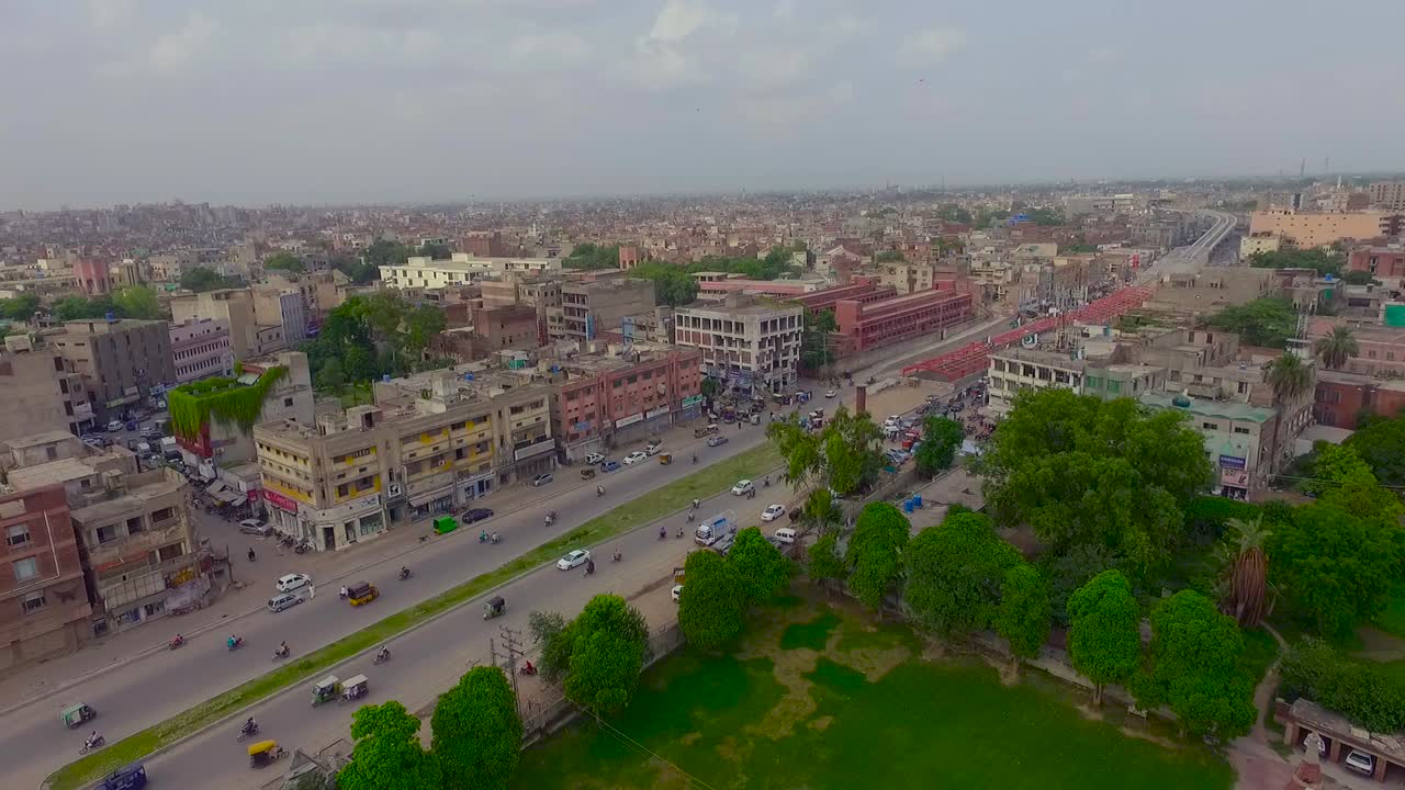 vista aérea de la ciudad y una calle concurrida con estación de metro y sobrevuelo, árboles verdes y hierba con la carretera