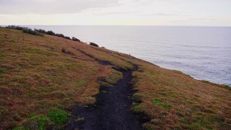 Grassy-Mountain-Slope-Overlooking-The-Calm-Blue-Ocean-In-Crescent-Head---Sunset-In-New-South-Wales,-Australia---wide-shot