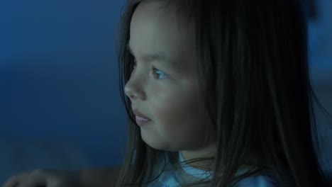 a young girl sits in front of a computer, displaying strong emotions. the scene captures her expressive reaction during an engaging moment, set in a cozy indoor environment