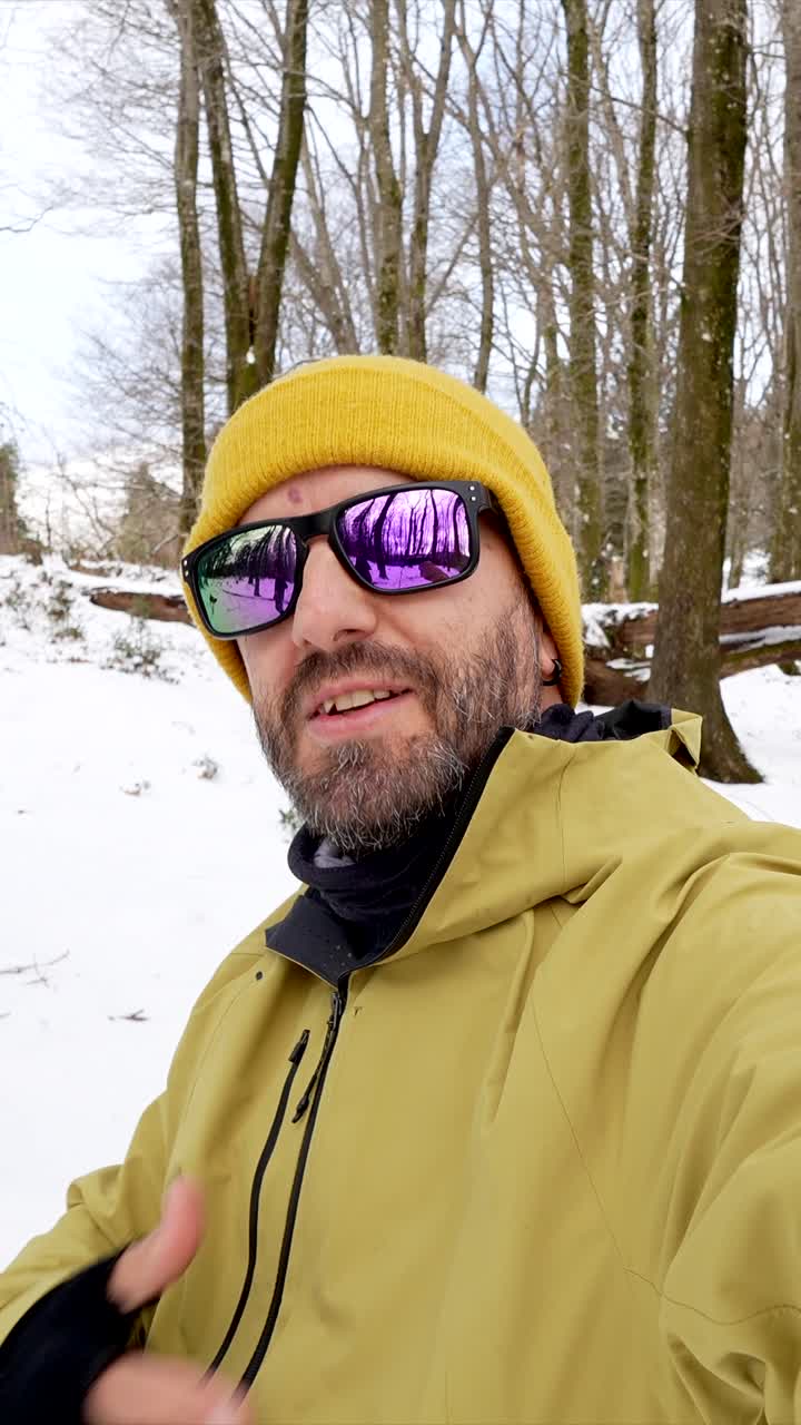 Man in winter landscape with sunglasses and yellow hat