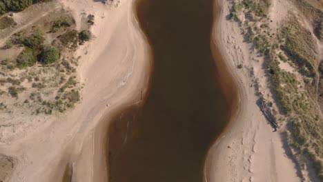 Drone-view-over-a-stream-leading-out-into-the-ocean