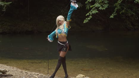 Anime-Cosplayerin-Mit-Ihrer-Peitsche-In-Der-Natur-An-Einem-Erstaunlich-Klaren-Wasserstrom