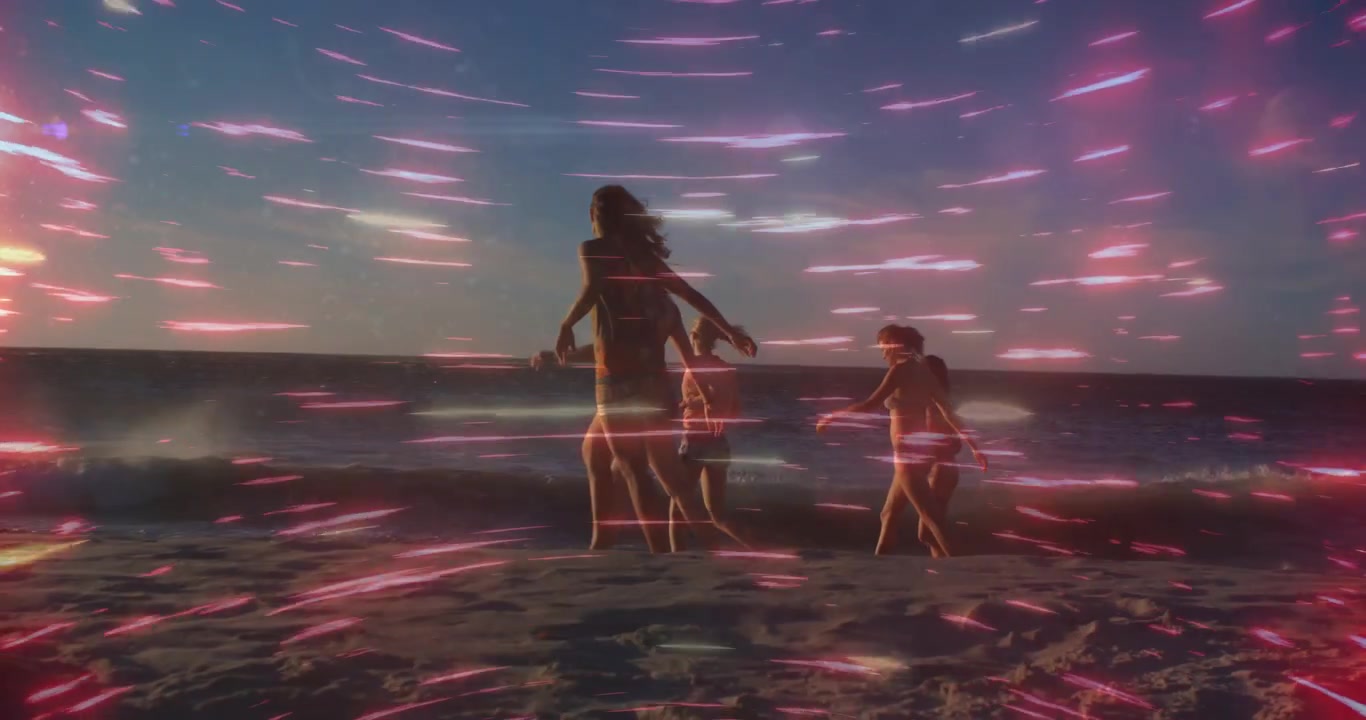 Tre donne che camminano nell'oceano al tramonto, con un bagliore che crea strisce rosa che le avvolgono, di fronte al mare, viaggio