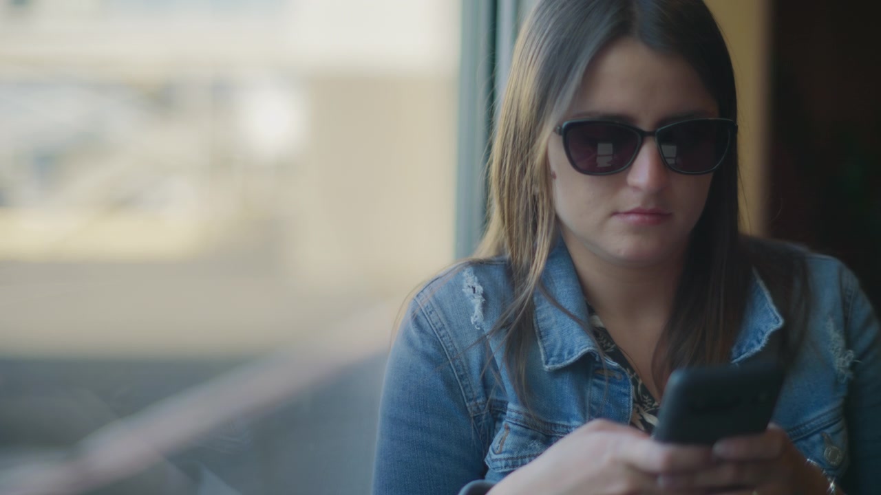Mujer joven navegando en redes sociales mientras espera para embarcar en la puerta.