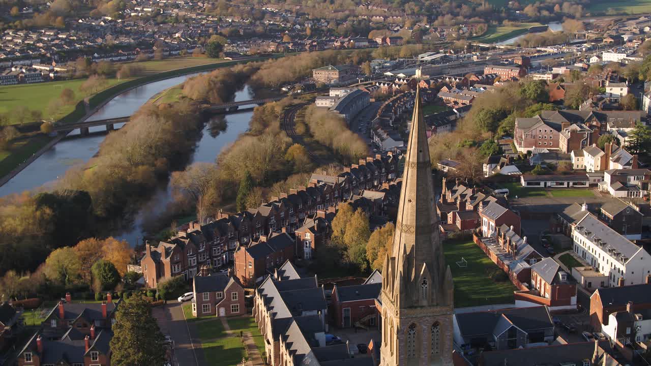 Sweeping aerial view of downtown Exeter, UK. A steeple of a church in the foreground, and the river Exe, the quay, and Exewick in the background