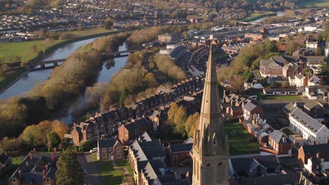 sweeping aerial view of downtown exeter, uk. a steeple of a church in the foreground, and the river exe, the quay, and exewick in the background