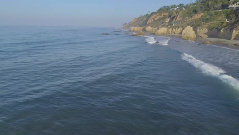 Aerial-shots-of-El-Matador-beach-over-breaking-waves-and-rocks-on-a-hazy-summer-morning-in-Malibu,-California