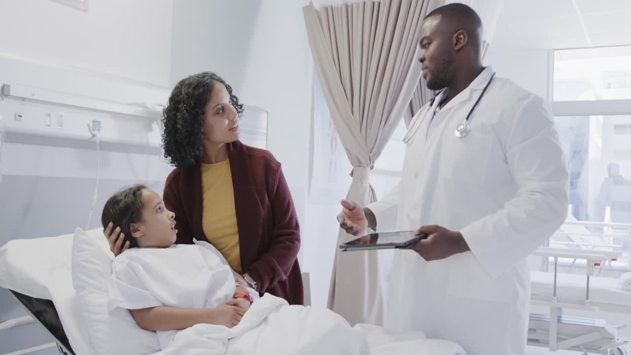 Worried diverse mother with her sick daughter patient talking to doctor in hospital in slow motion