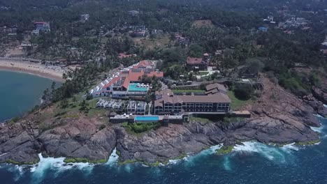 The-Raviz-Kovalam-Hotel-At-The-Shoreline-In-Kerala,-India---aerial-drone-pullback