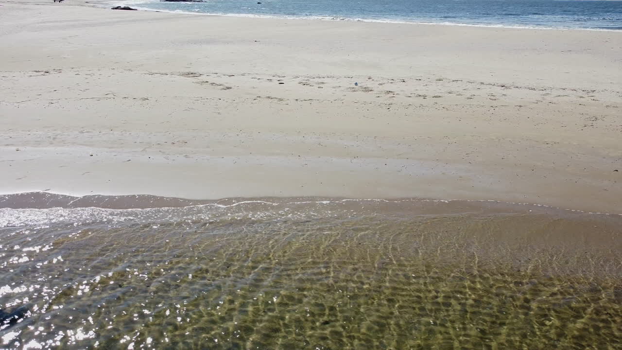 Drone flying across beach with lagoon in lower third and ocean in upper third