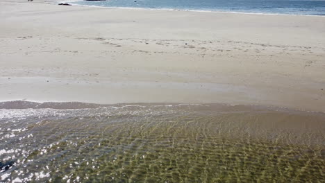 drone flying across beach with lagoon in lower third and ocean in upper third
