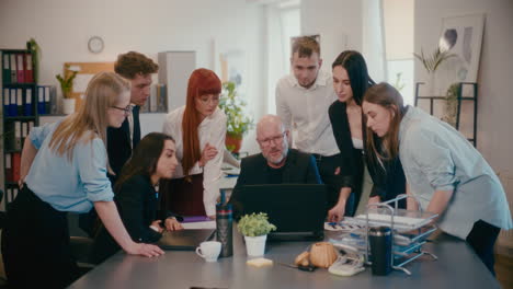 manager erklärt mitarbeitern über laptop im büro.