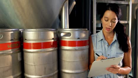 Female-brewer-maintaining-record-on-clipboard-4k