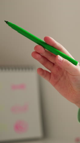 girl removes cap from green felt-tip pen. junior schoolgirl draws picture studying or spending free time. child develops fine motor skills of hands