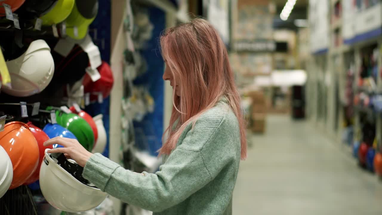Giovane ragazza che cerca un casco protettivo colorato in una ferramenta